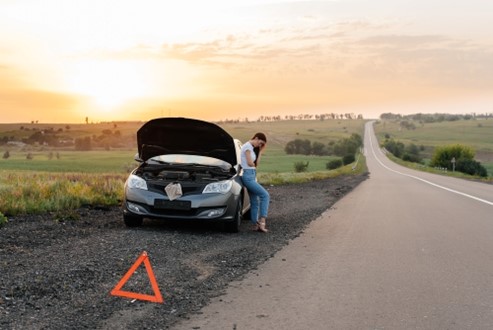 Woman waits for help with non-running car.