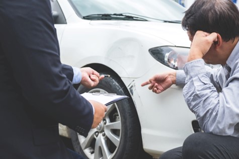 Person assesses accident-damage on car